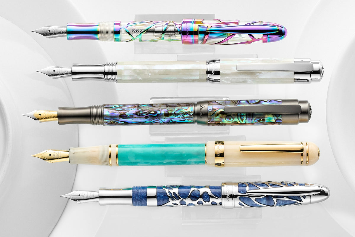 A variety of Laban fountain pens, lined up and posted, on a white background.